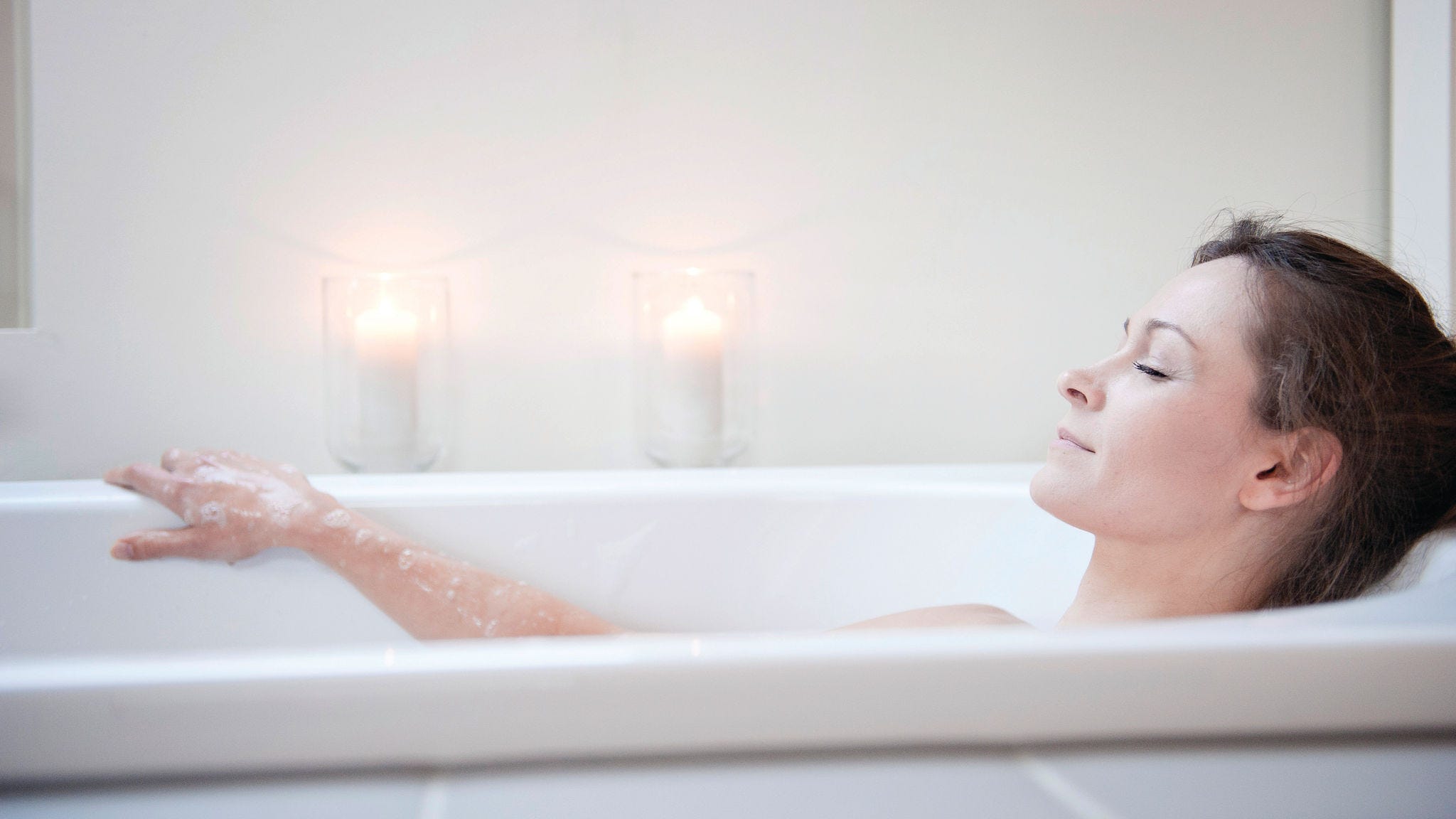 Woman relaxing in the bath tub containing water that's heated with renewable energy using Daikin's domestic hot water heat pumps