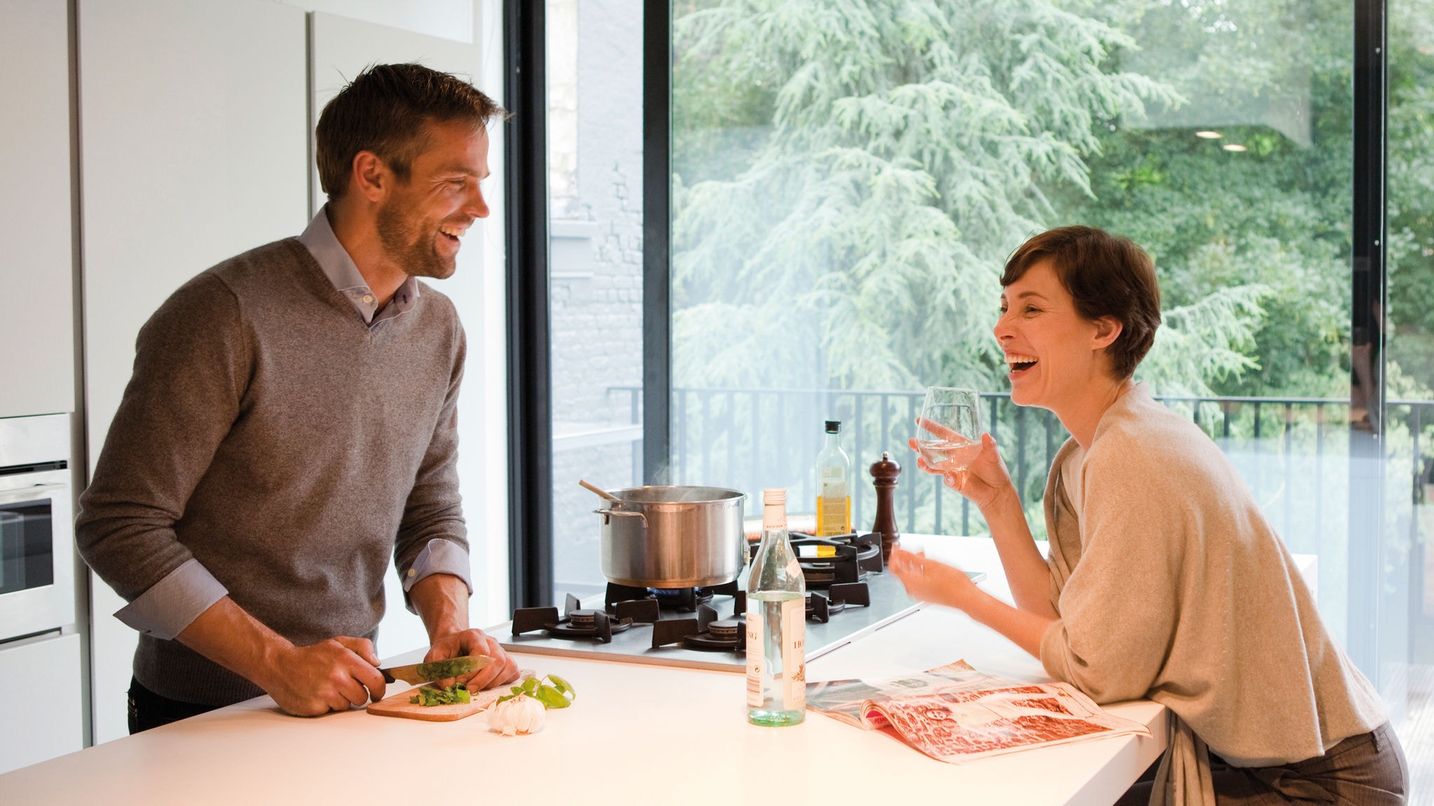 Couple laughing and making diner in their warm kitchen thanks to their heating technology