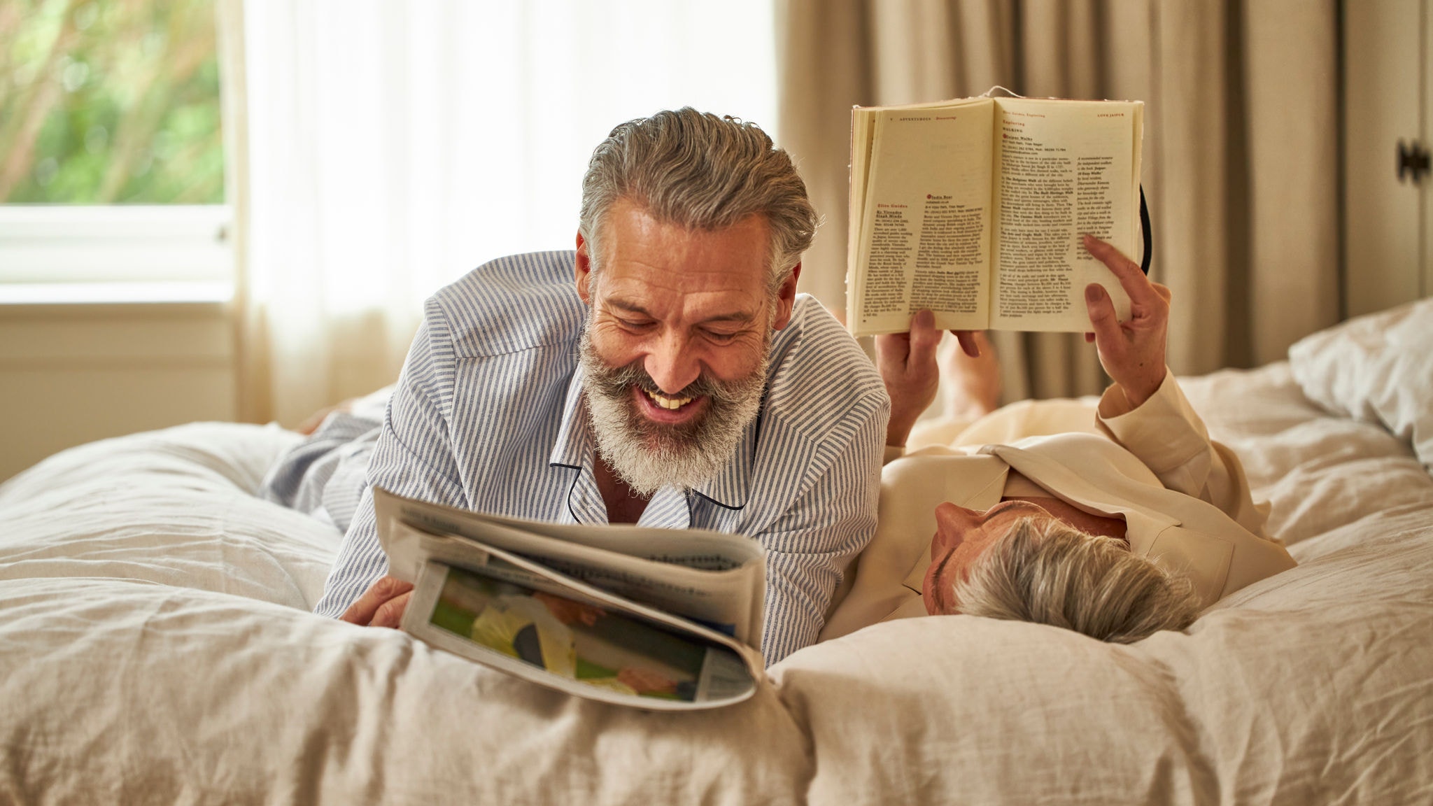 Middle-aged couple happily relaxing on their bed and enjoying the perfect temperature