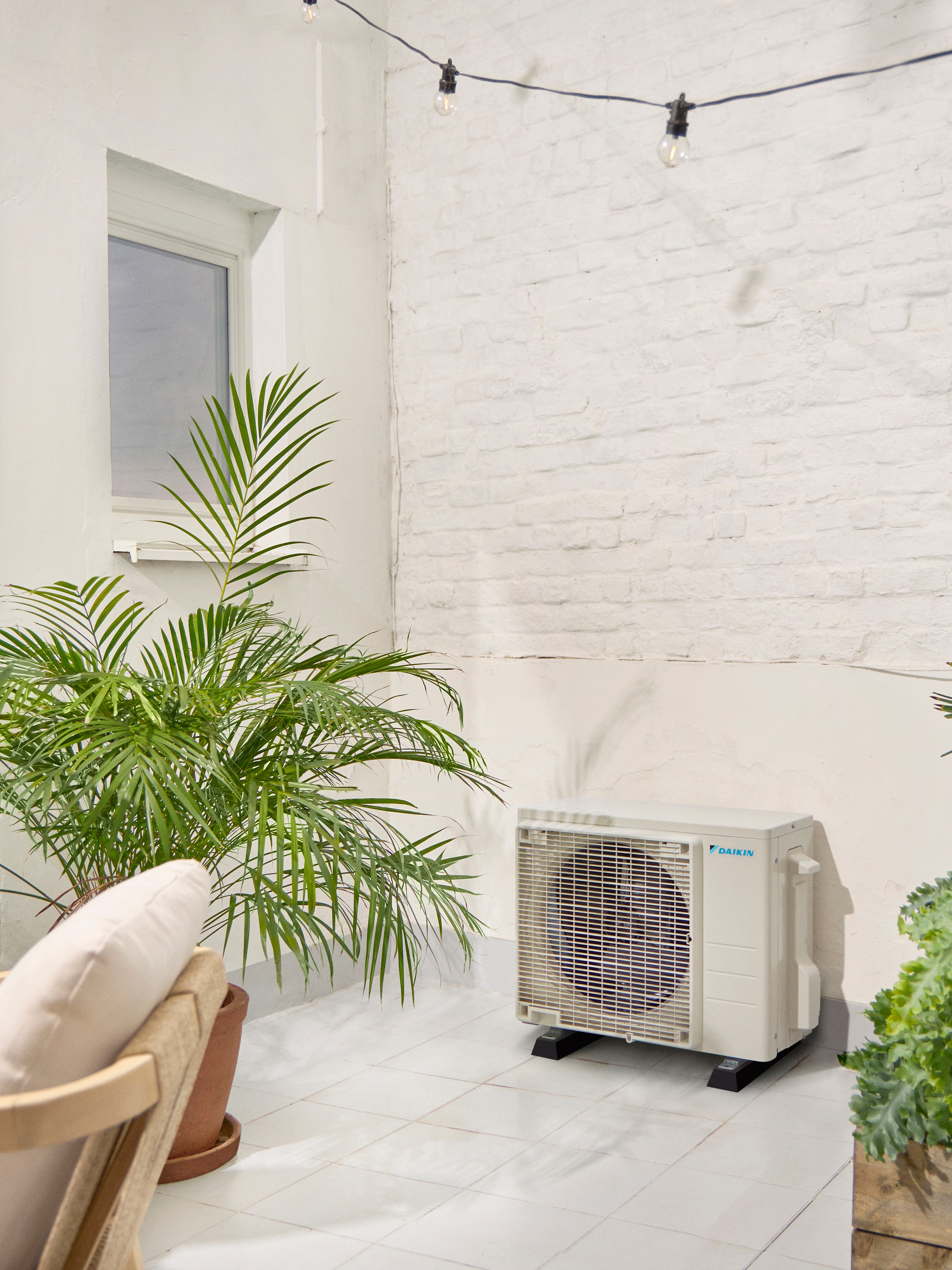 Daikin outdoor unit on white terrace with a plant