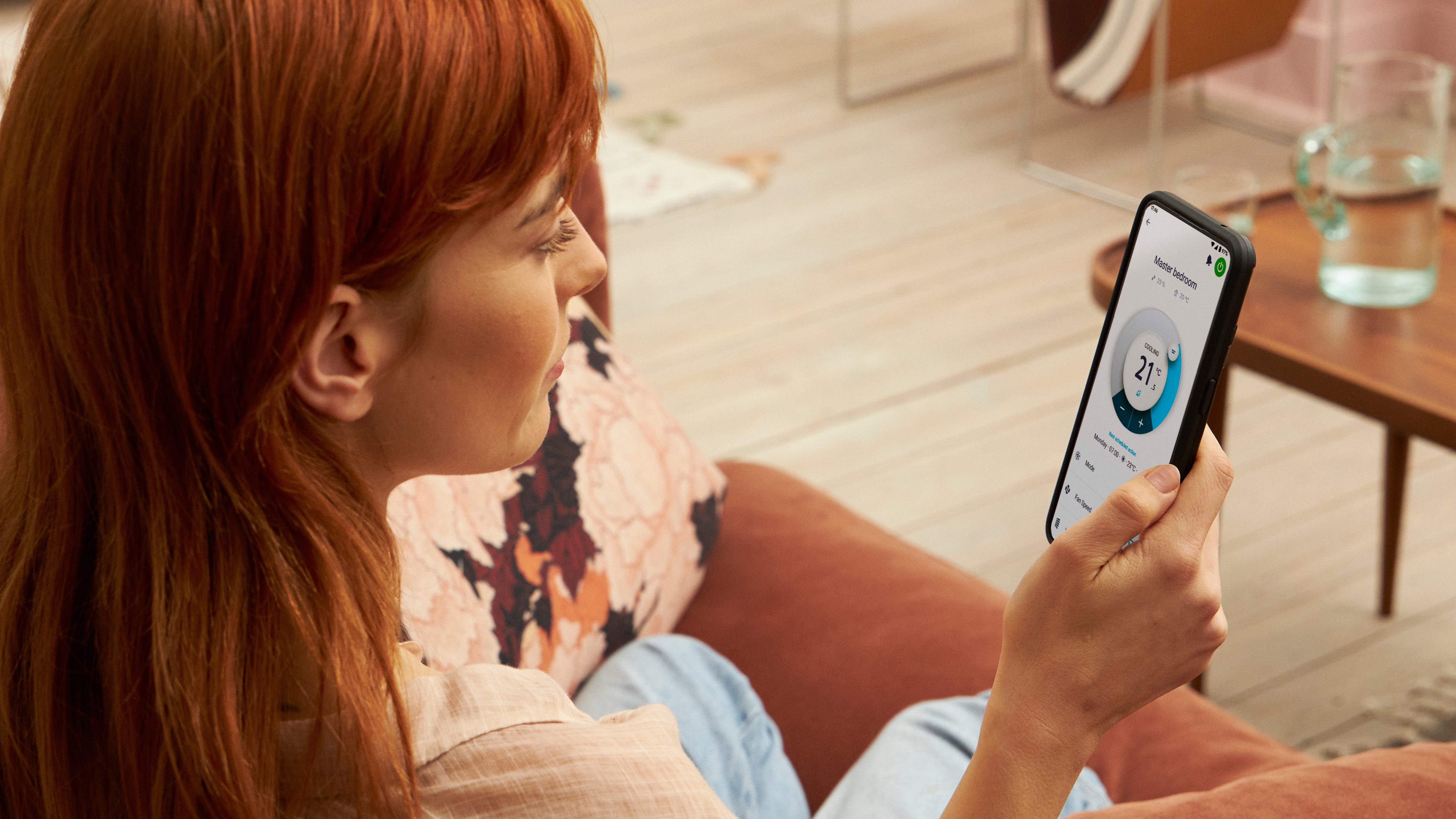 Lady holding het smartphone and using the Onecta app to control the room temperature
