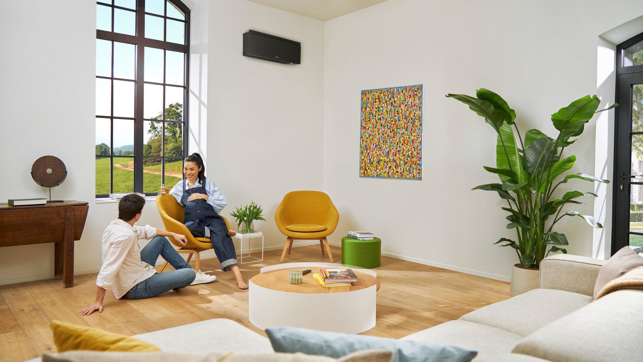 Pregnant couple casually talking while the woman is sitting on a chair