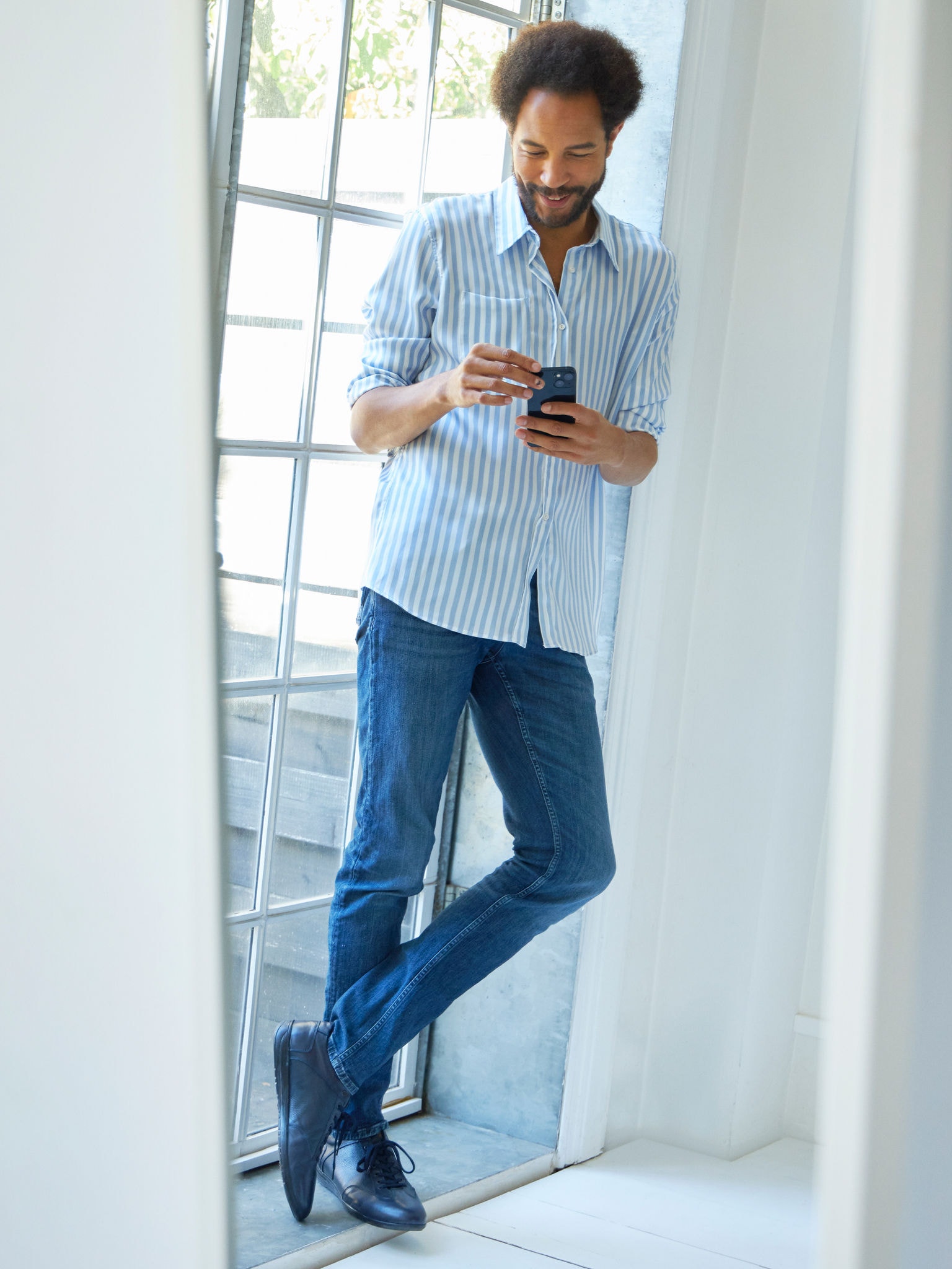 Man standing close to a window viewing air conditioners on the virtual experience centre on his smartphone