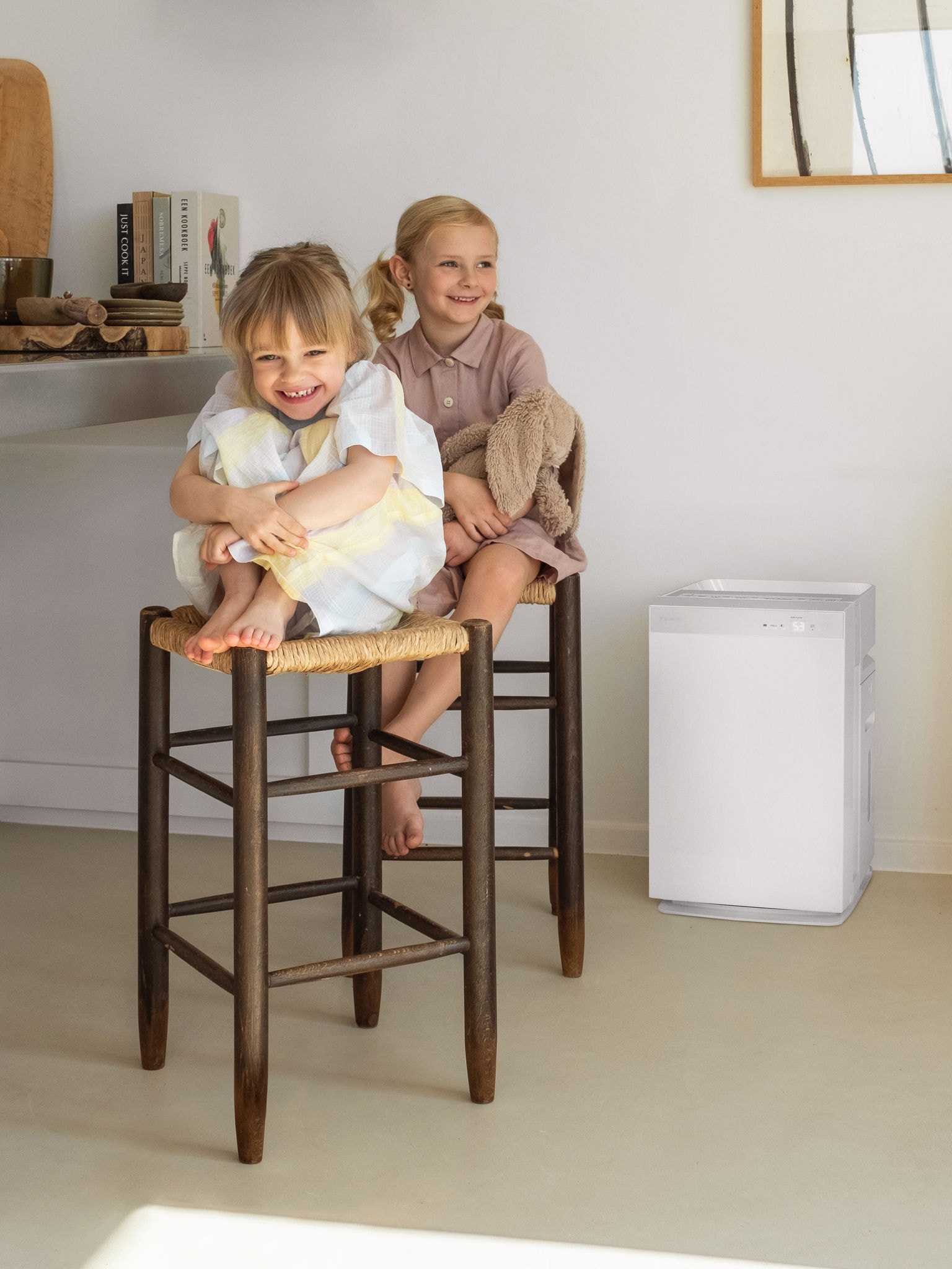 Mother holding her baby while sitting on the couch next to an air purifier