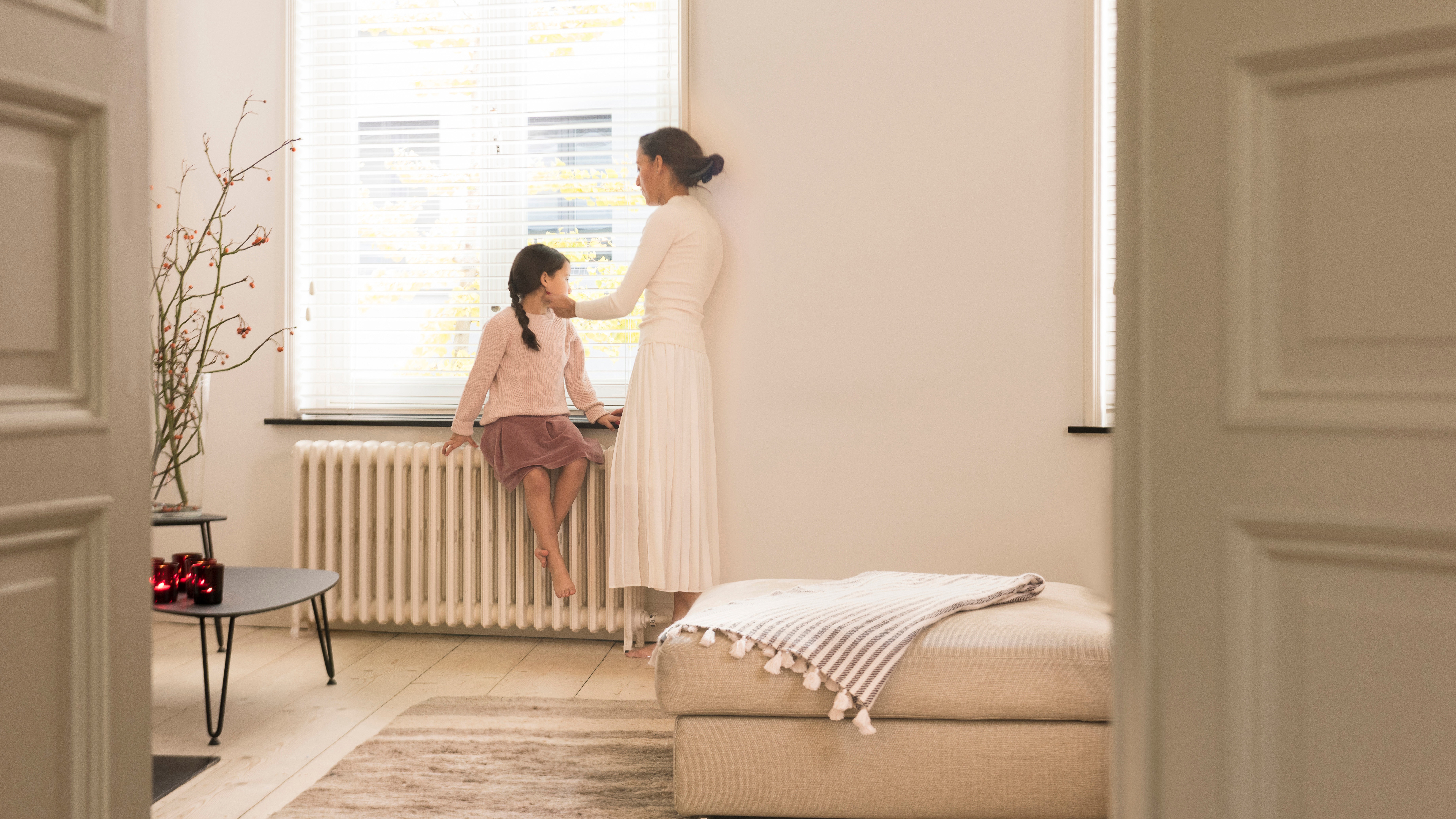 Mom and daughter talking and warming up against the radiator