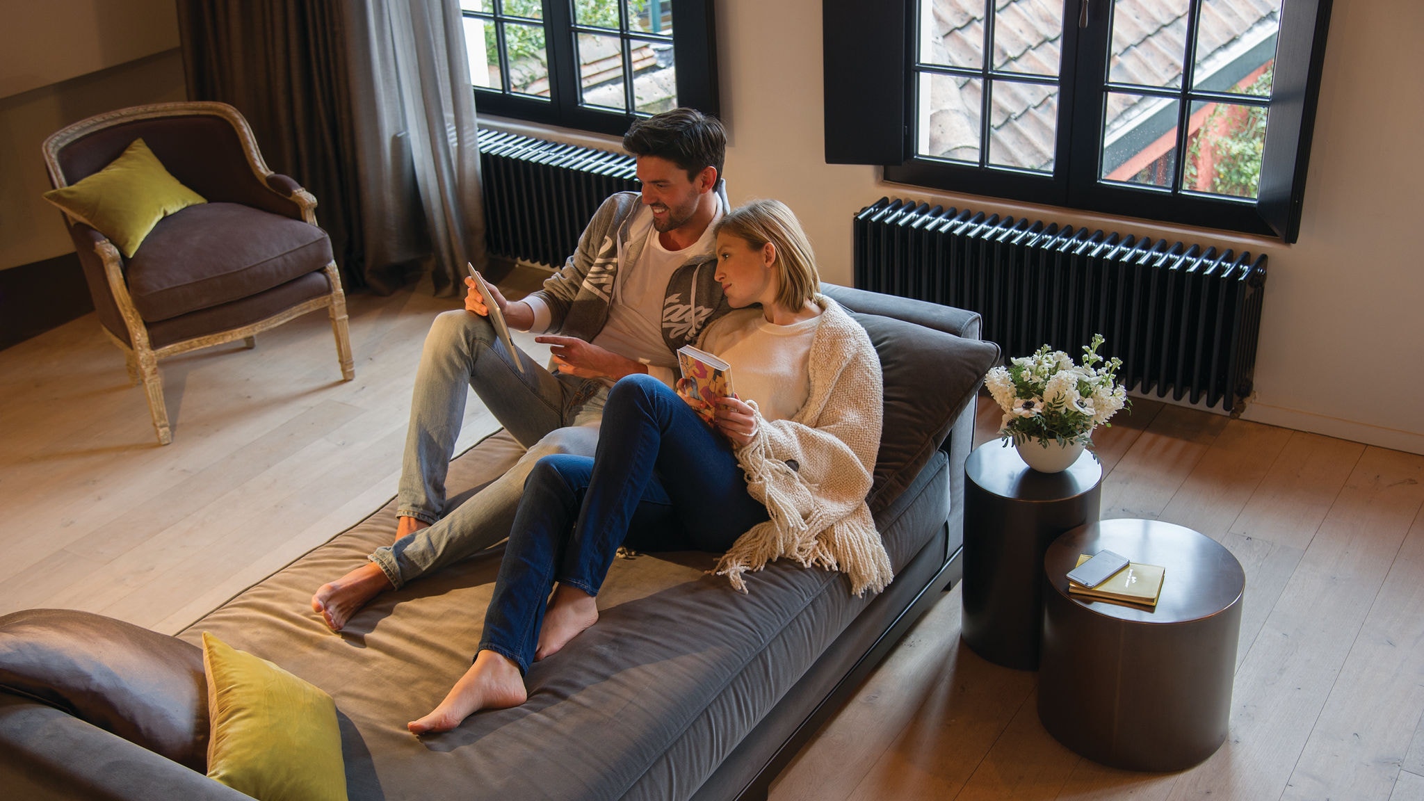 Couple relaxing on a couch and looking at something on their tablet
