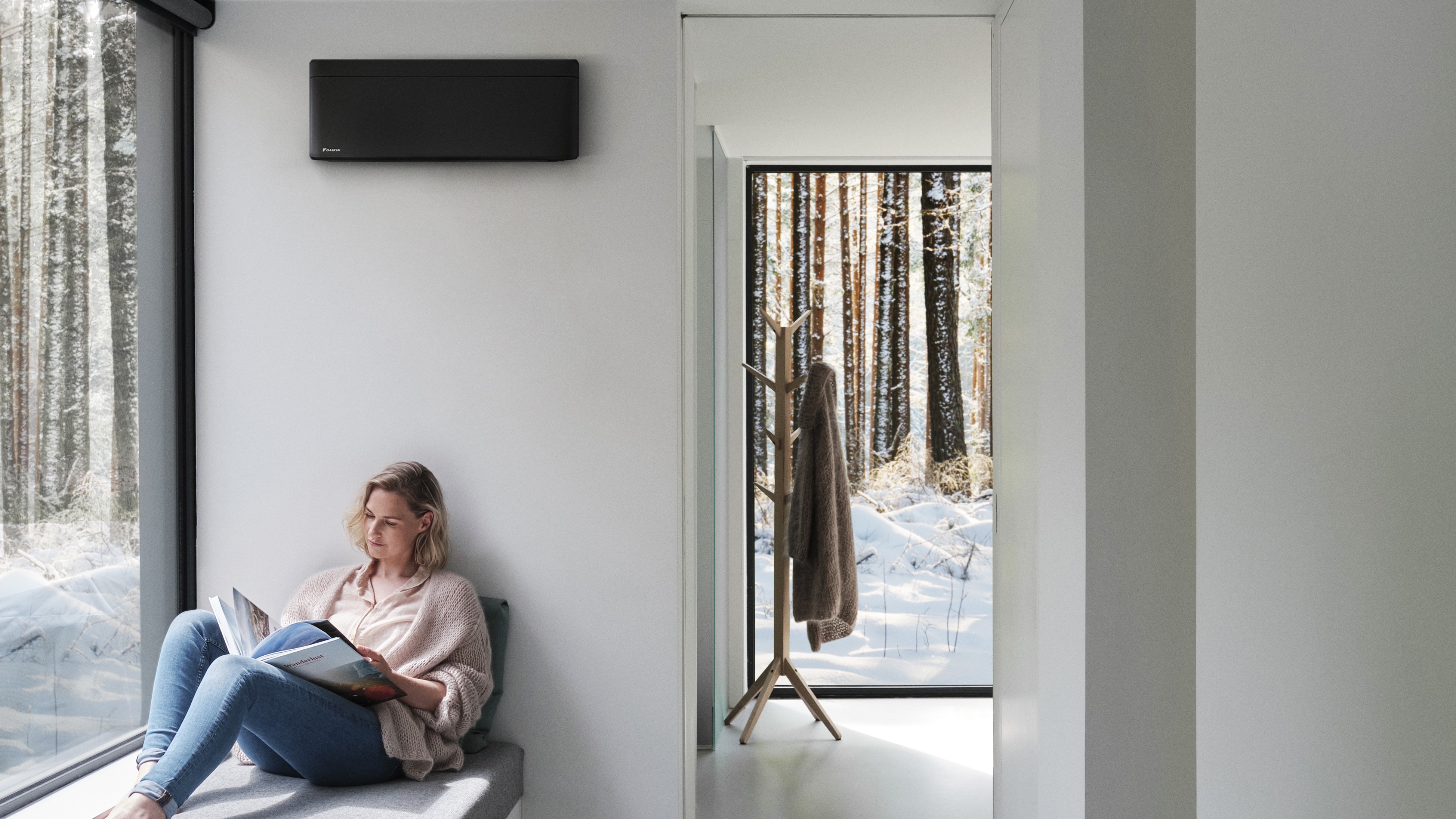 Woman reading and enjoying perfect room temperature because of her wall-mounted climate solution
