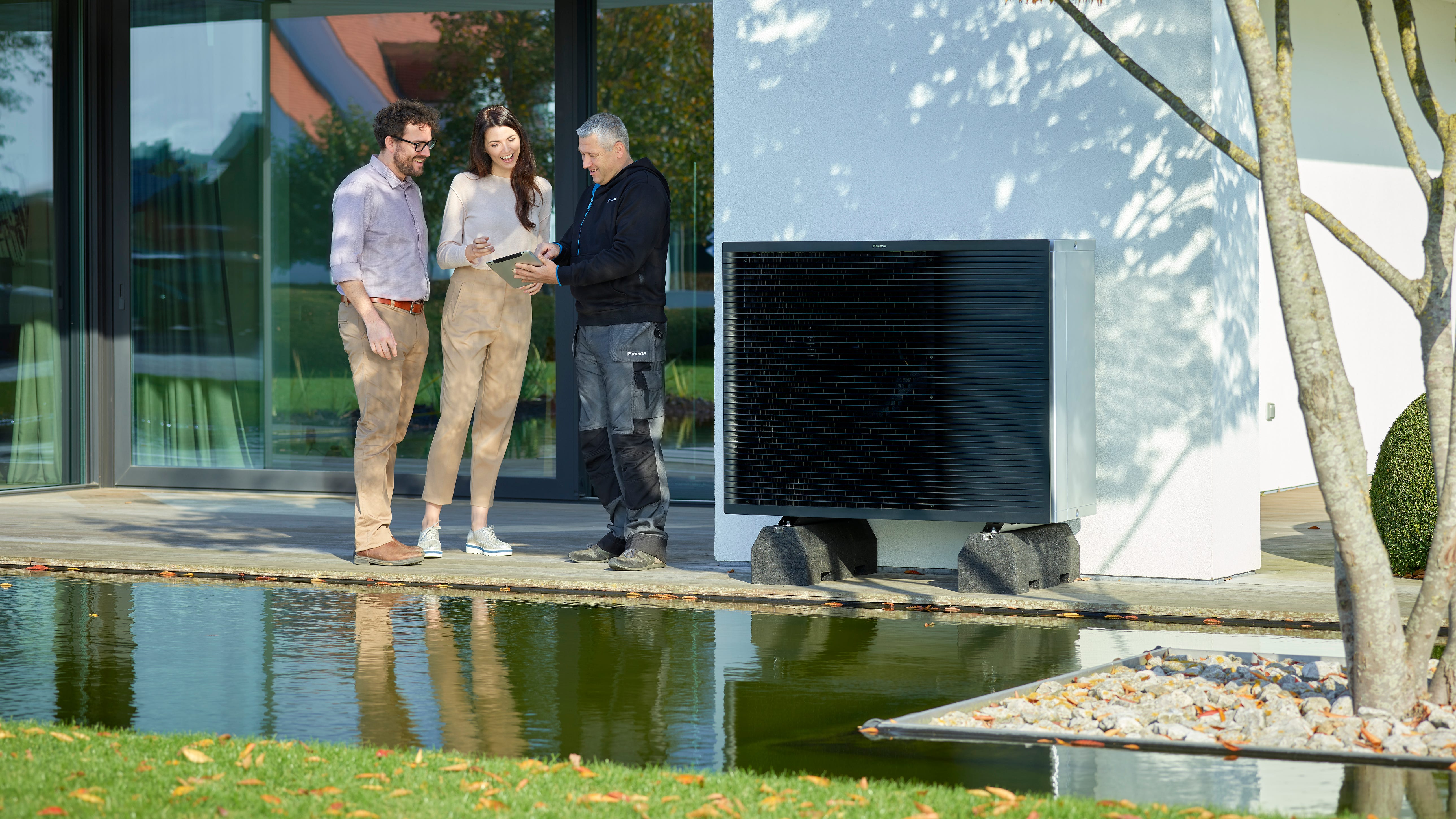 Couple talking to an installer in their garden next to a Daikin Altherma outside unit
