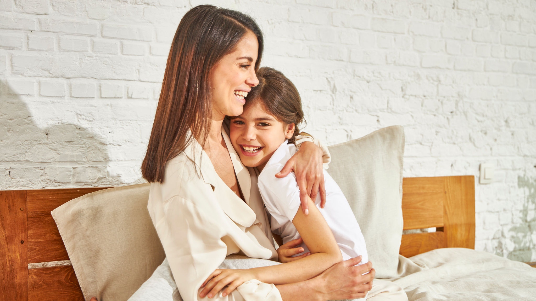 Mother hugging her daughter on the bed enjoying the temperature